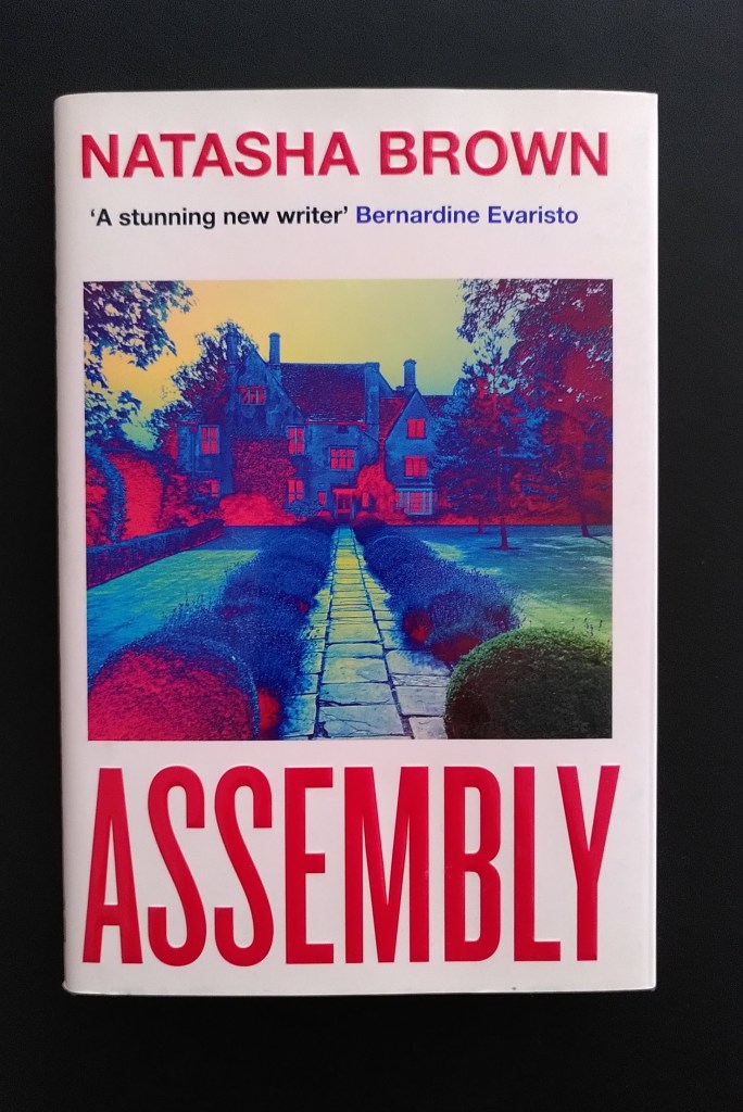 Das Cover von Natasha Browns Assembly zeigt eine Einfahrt zu einer Villa mit Garten, farblich ist es rot-grün-blau bearbeitet