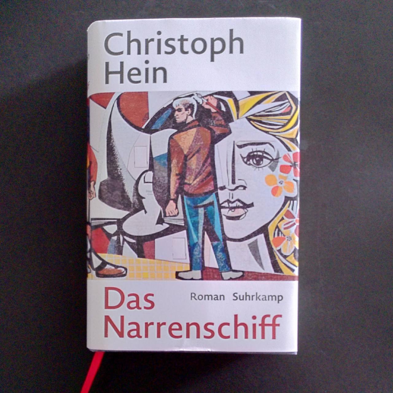 Das Bild zeigt das Cover von Christoph Heins Das Narrenschiff. Darauf ist ein Wandmosaik im Stil des sozialistischen Realismus zu sehen.